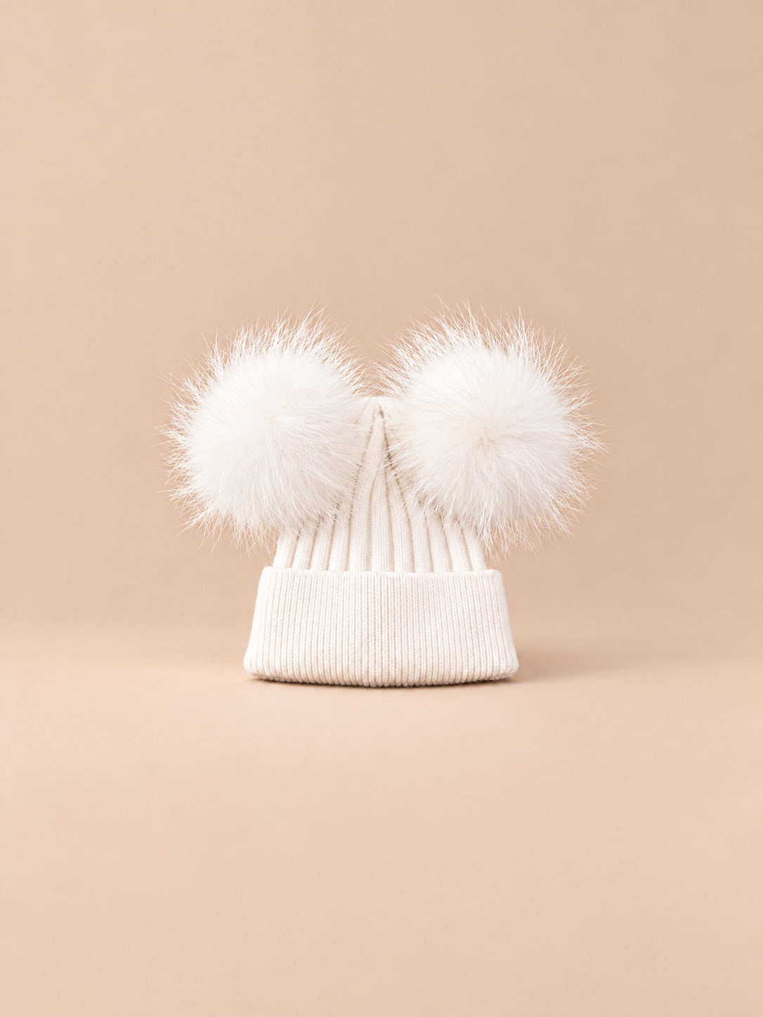 Bonnet double pompon, blanc, pompons assortis, vue de face sur fond pêche sable.