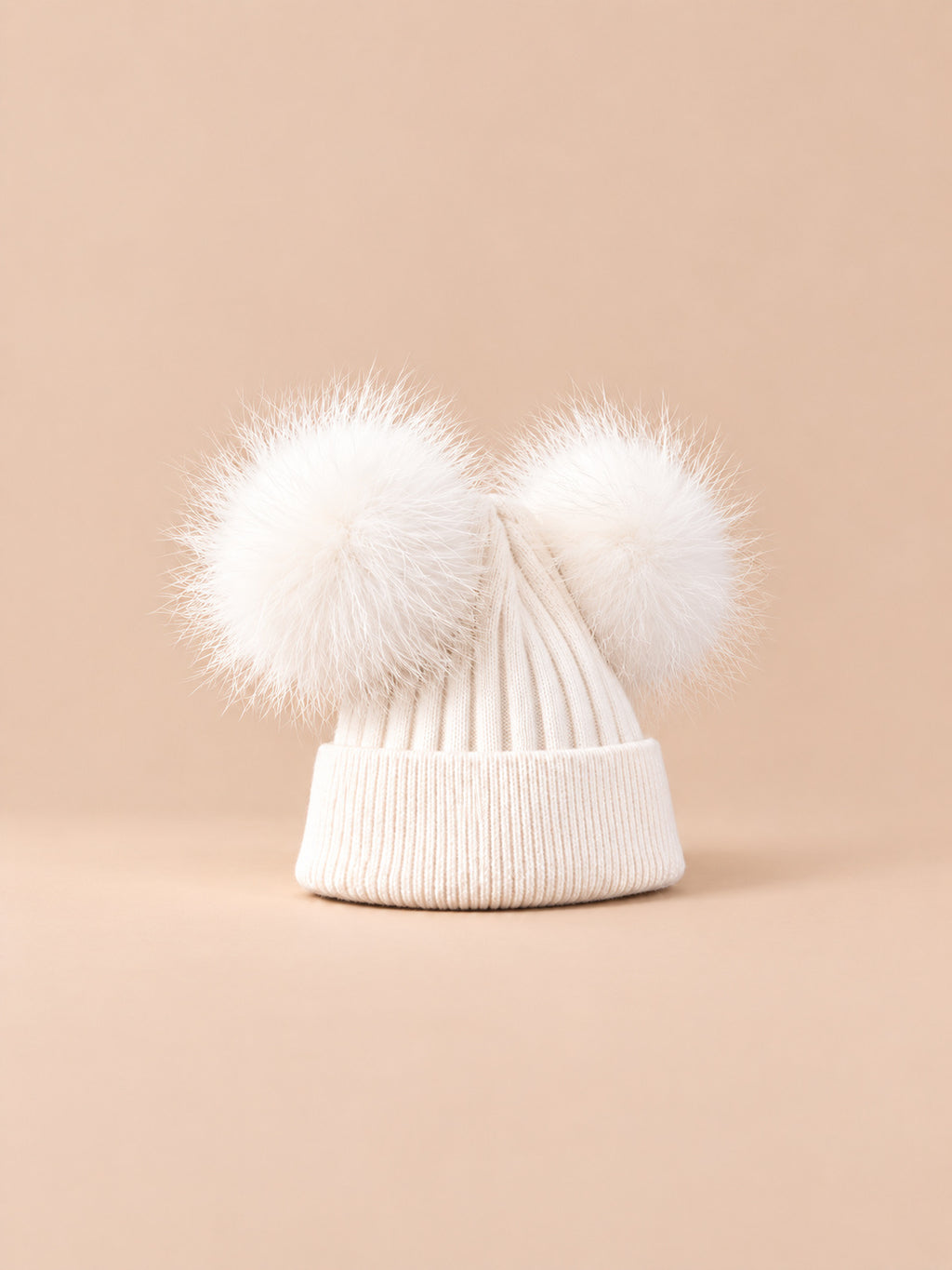 Bonnet double pompon, blanc, pompons assortis, vue de trois quarts sur fond pêche sable.