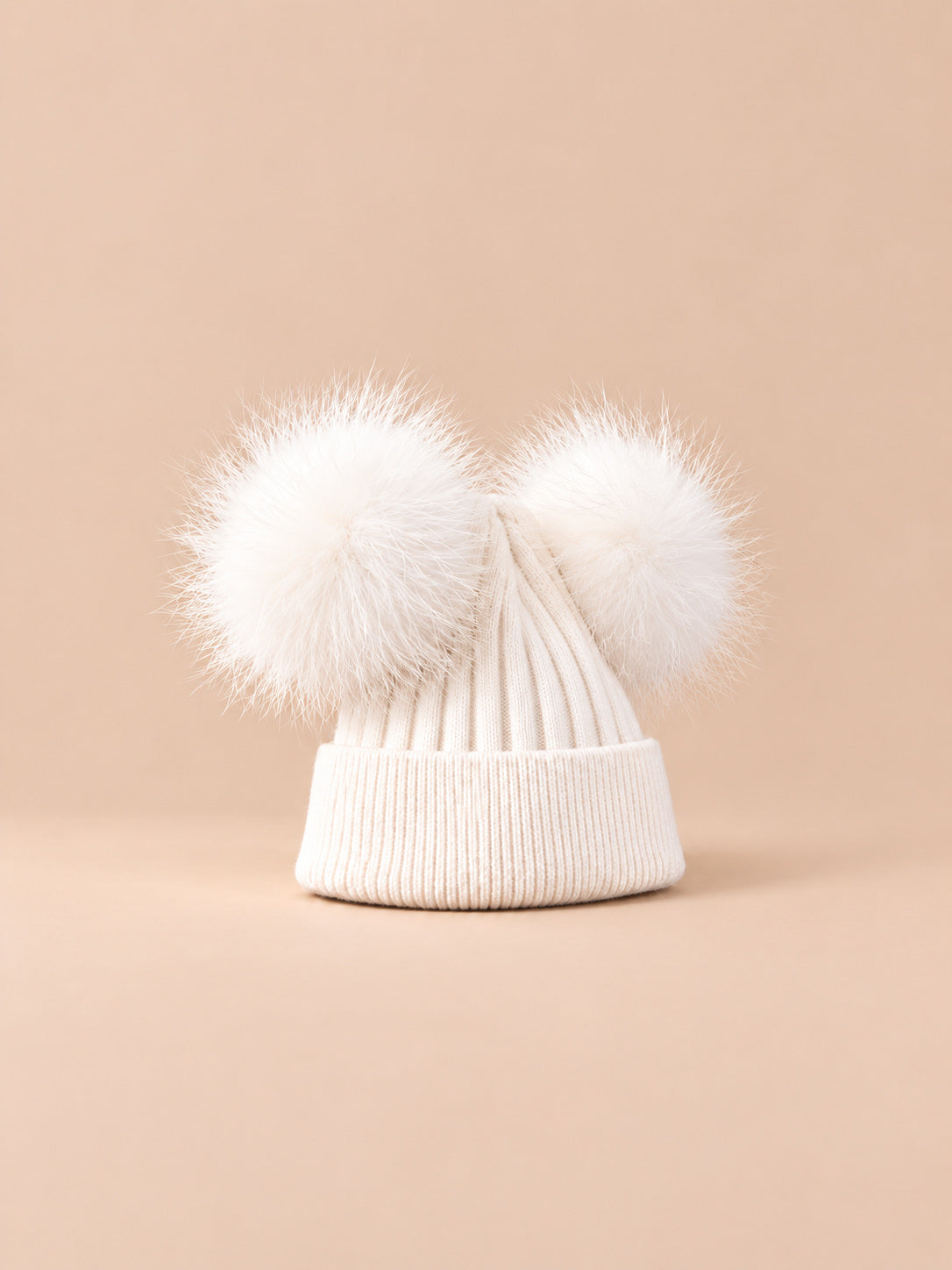 Bonnet double pompon, blanc, pompons assortis, vue de trois quarts sur fond pêche sable.