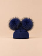 Bonnet double pompon, bleu marine, pompons assortis, vue de face sur fond pêche sable.