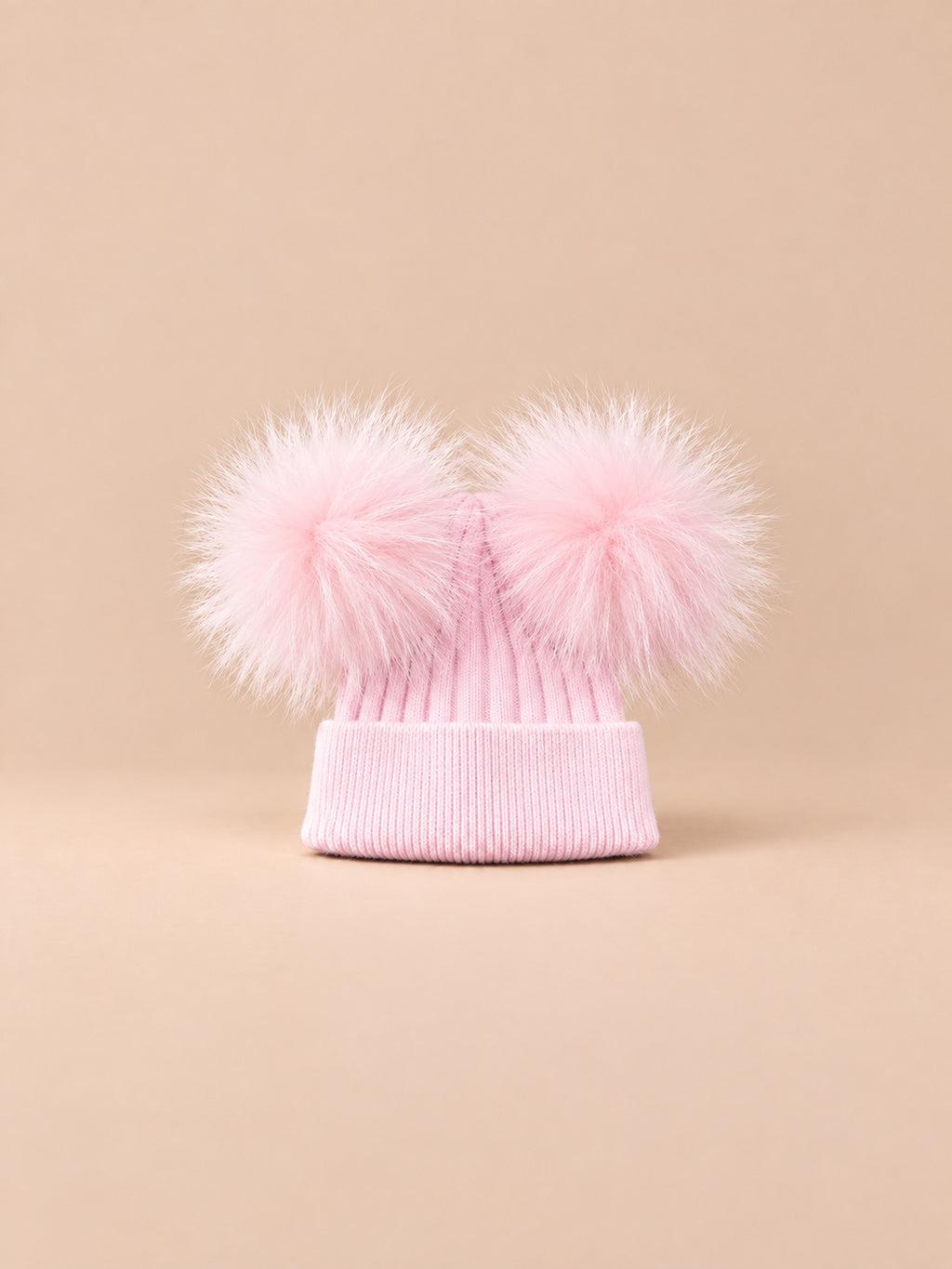 Bonnet double pompon, rose, pompons assortis, vue de face sur fond pêche sable.