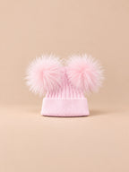 Bonnet double pompon, rose, pompons assortis, vue de face sur fond pêche sable.