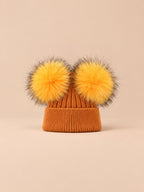 Bonnet double pompon, roux, pompons assortis, vue de face sur fond pêche sable.