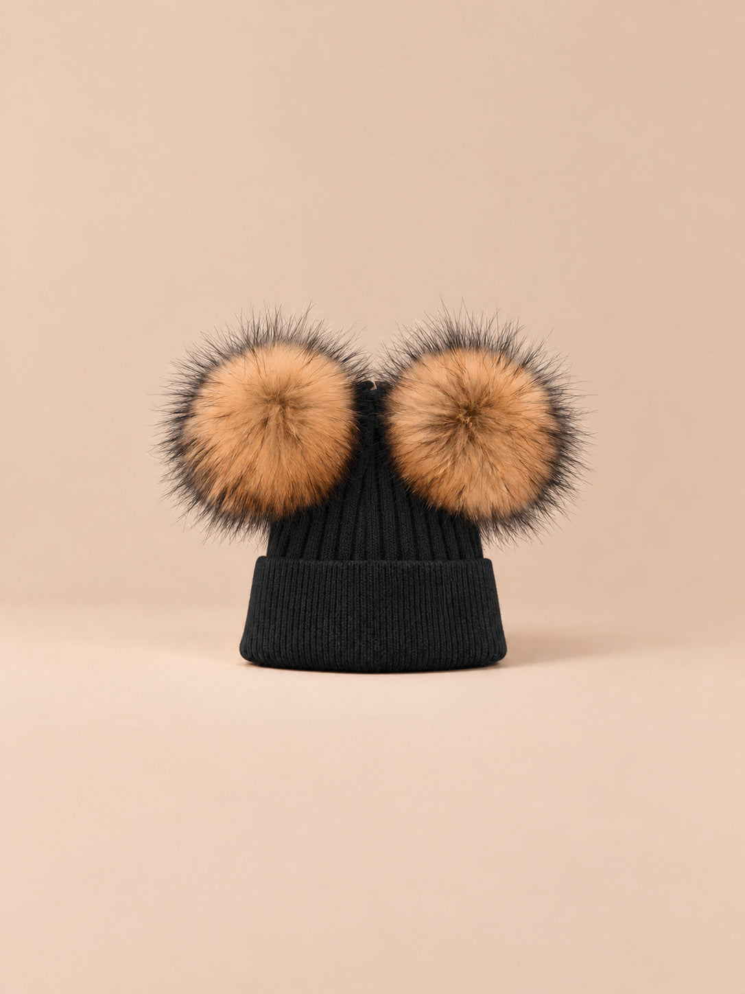 Bonnet double pompon, vert foncé, pompons naturels, vue de face sur fond pêche sable.