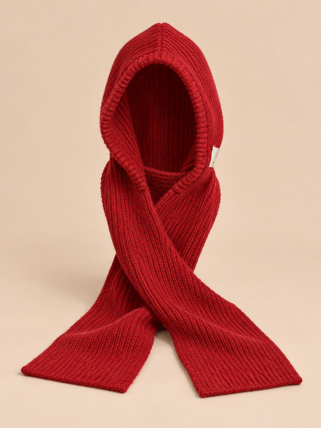 Cagoule bonnet-écharpe rouge en maille, vue de face sur fond pêche sable