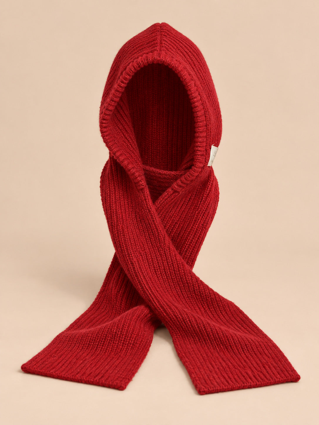 Cagoule bonnet-écharpe rouge en maille, vue de face sur fond pêche sable
