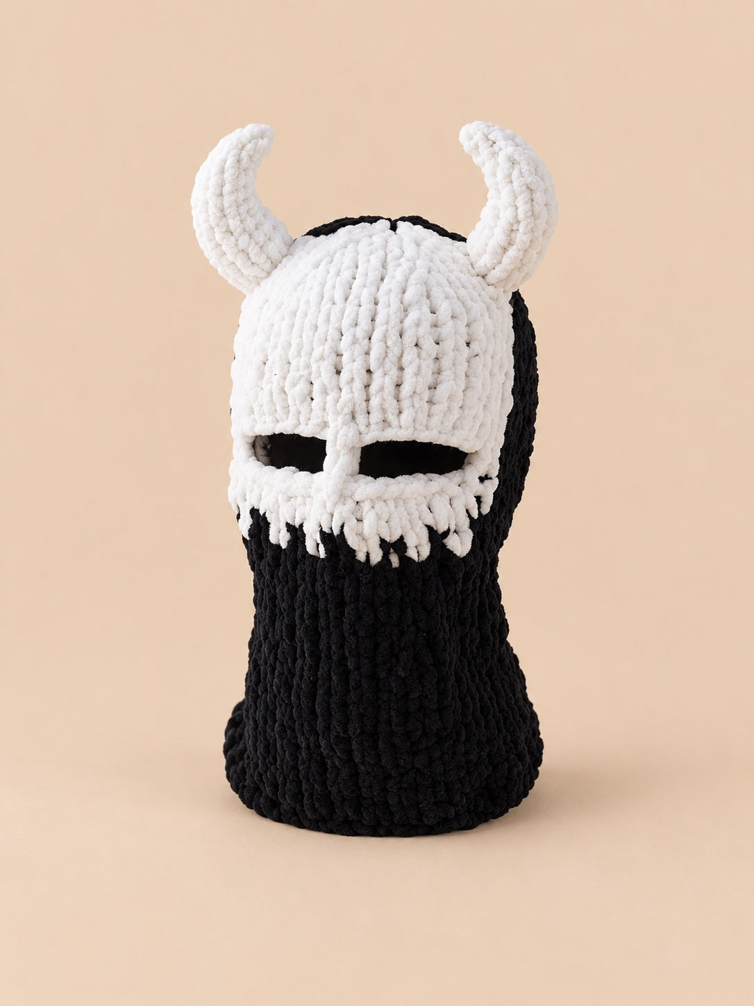 Cagoule crochet cornes de diable modèle 5 noire et blanche, vue de face sur fond pêche sable