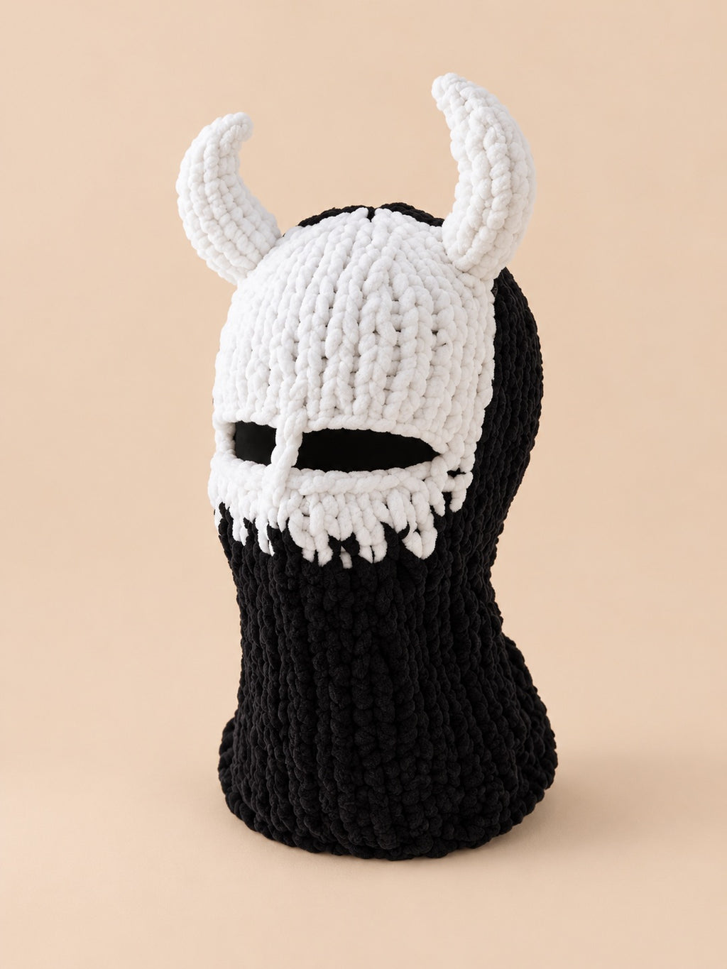 Cagoule crochet cornes de diable modèle 5 noire et blanche, vue trois quarts sur fond pêche sable