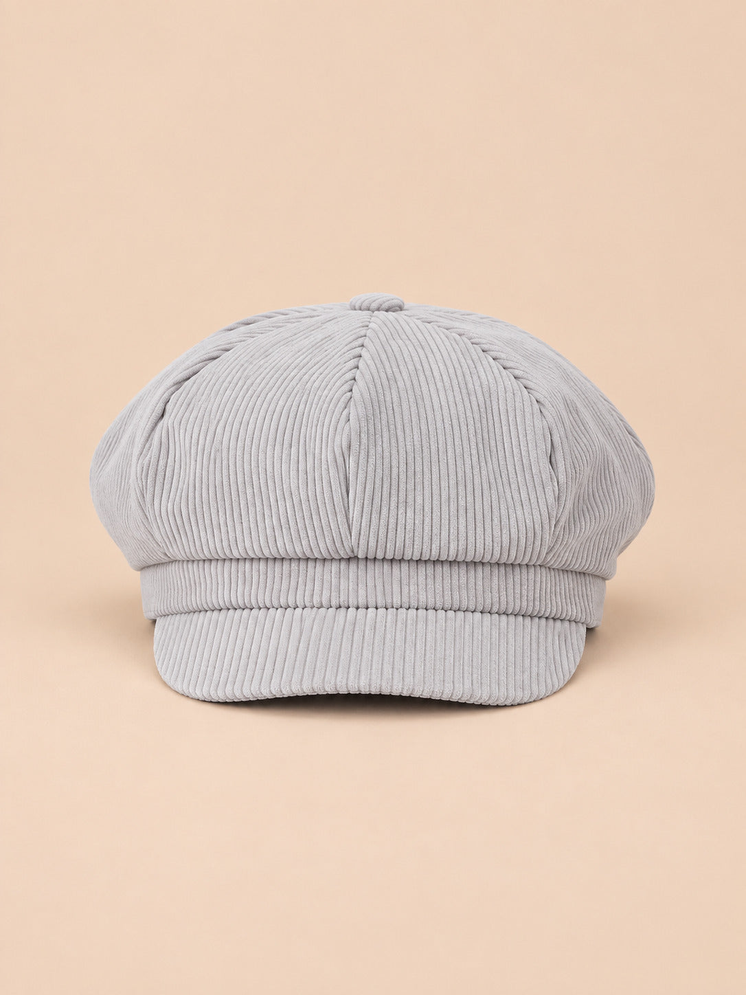 Casquette gavroche octogonale en velours côtelé gris, vue de face sur fond pêche sable