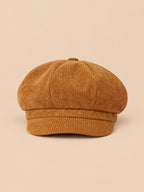 Casquette gavroche octogonale en velours côtelé jaune, vue de face sur fond pêche sable