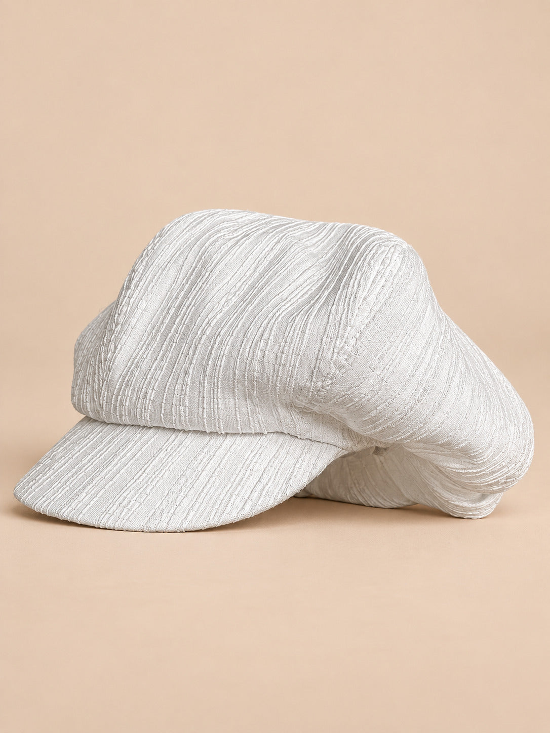 Casquette gavroche vintage blanc, vue de face sur fond pêche sable
