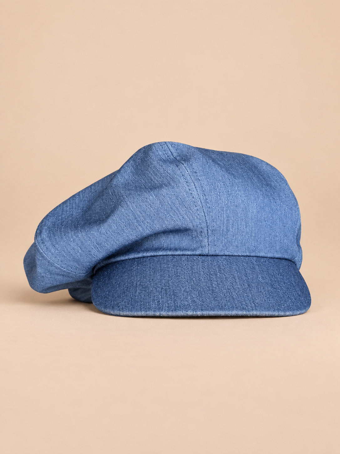 Casquette gavroche vintage bleu ciel, vue de face sur fond pêche sable