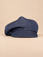 Casquette gavroche vintage bleu, vue de face sur fond pêche sable