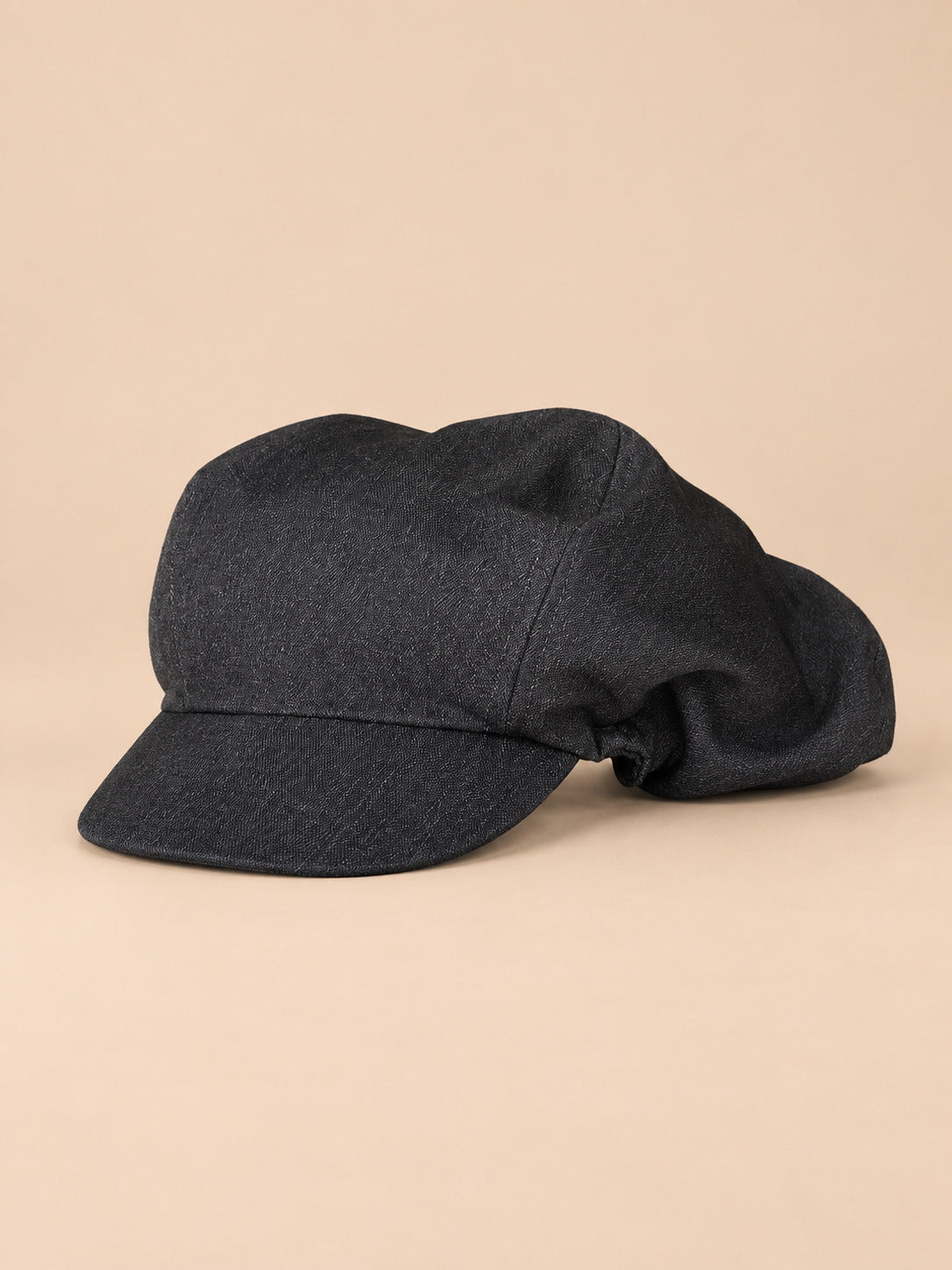 Casquette gavroche vintage gris fonce, vue de face sur fond pêche sable