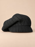 Casquette gavroche vintage noir, vue de face sur fond pêche sable