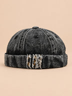Bonnet docker en denim noir, revers effiloché à détails léopard, vue de face.