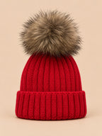 Bonnet enfant à pompon rouge, vue de face sur fond pêche sable