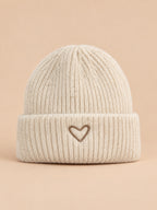 Bonnet enfant beige en maille, vue de face, fond pêche sable