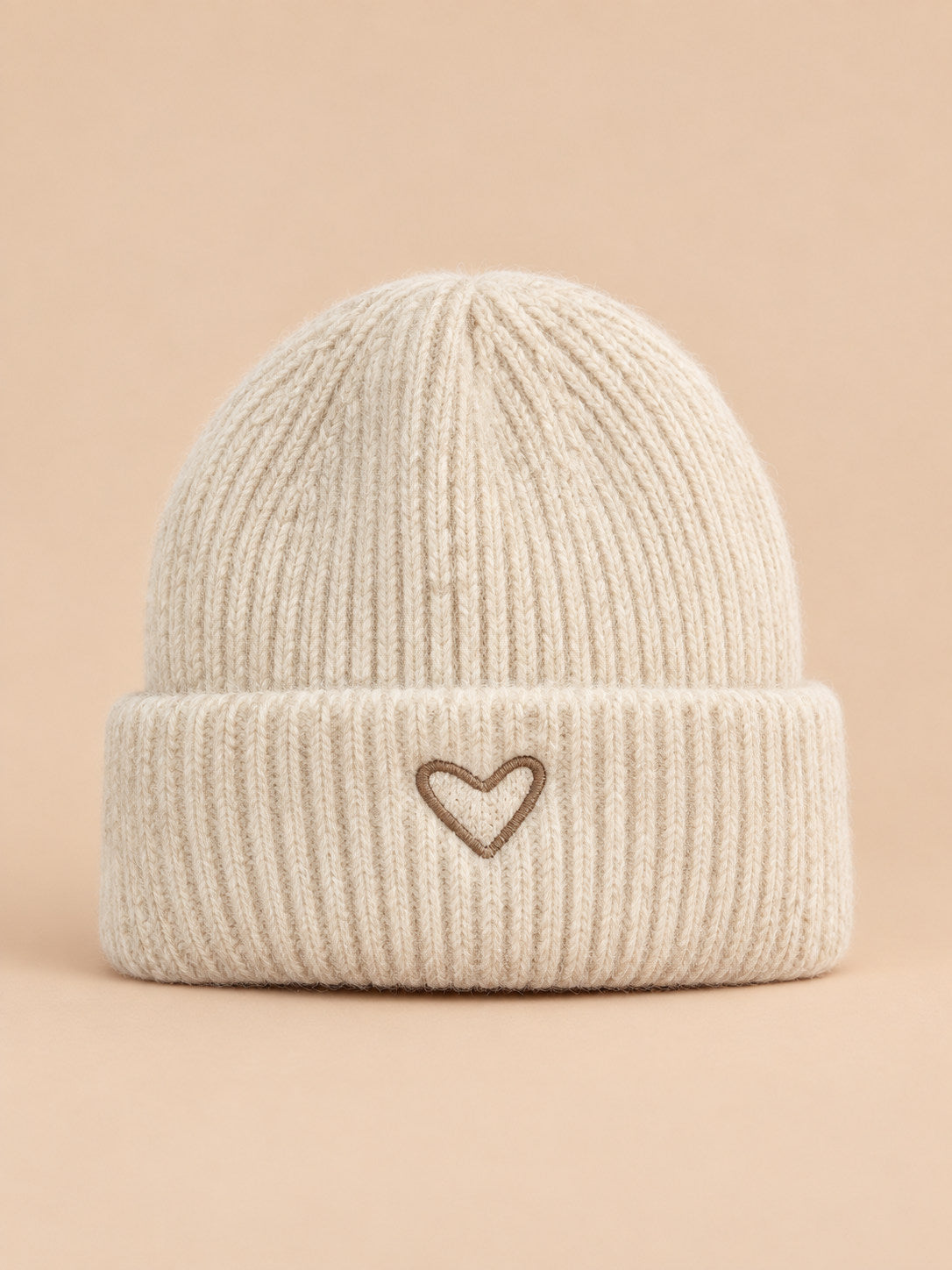 Bonnet enfant beige en maille, vue de face, fond pêche sable