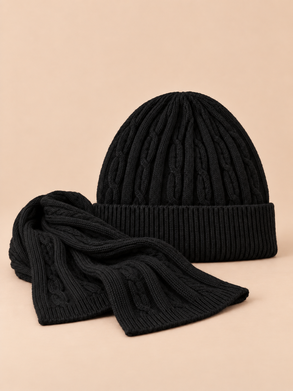 Ensemble bonnet à revers et écharpe en laine jacquard noire, vue de face sur fond pêche sable.