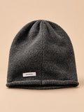 Bonnet femme en pure laine gris, vue de face, fond pêche sable