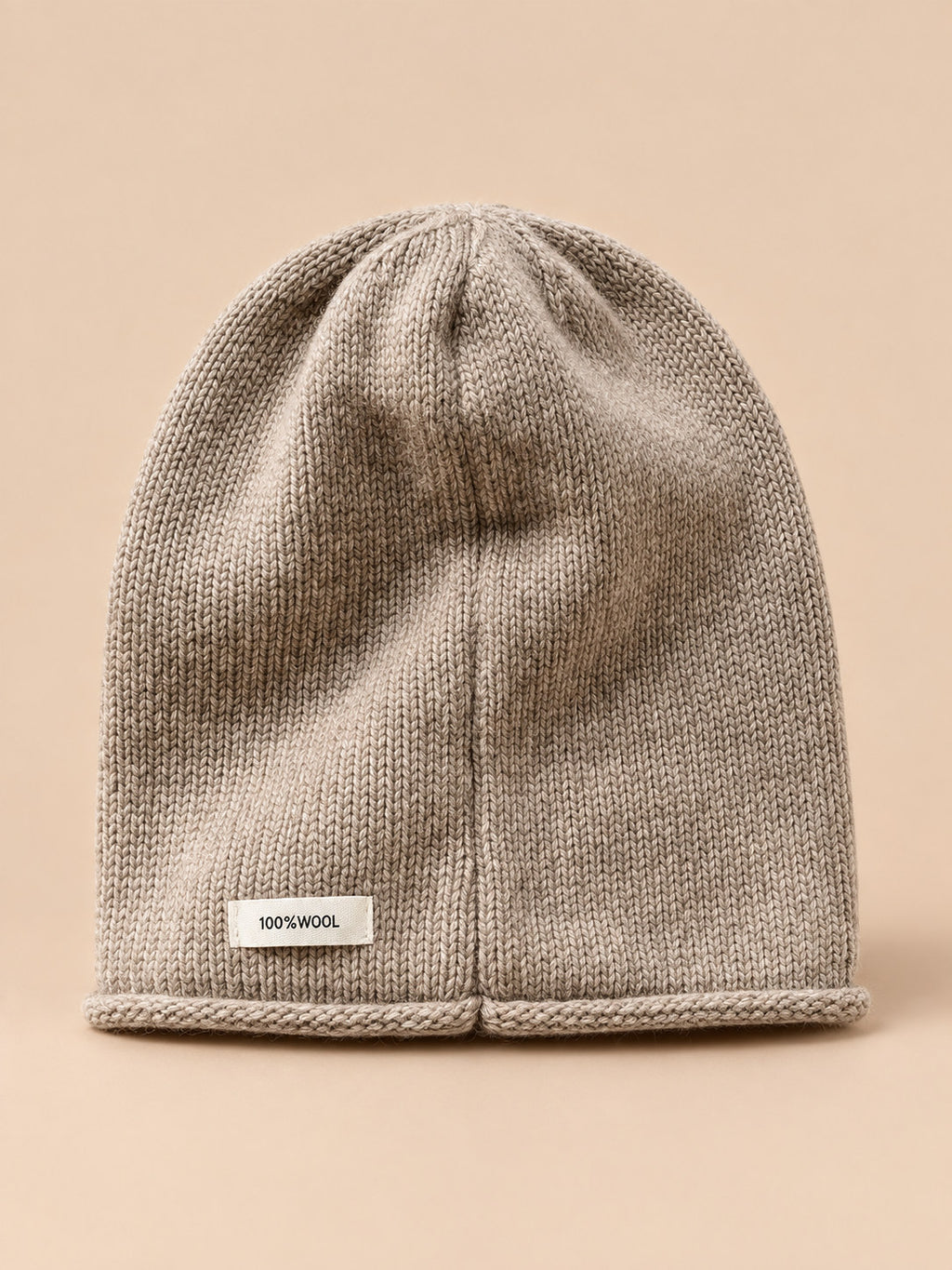 Bonnet femme en pure laine kaki, vue de face, fond pêche sable