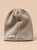 Bonnet femme en pure laine kaki, vue de face, fond pêche sable