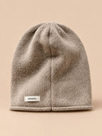 Bonnet femme en pure laine kaki, vue de face, fond pêche sable