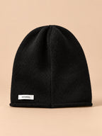 Bonnet femme en pure laine noir, vue de face, fond pêche sable