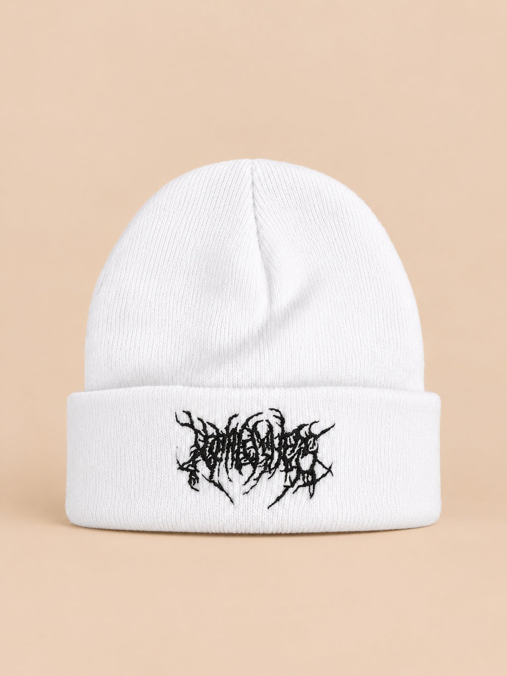 Bonnet en maille chaud blanc à broderie noire, vue de face sur fond pêche sable