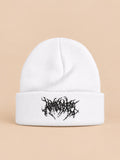 Bonnet en maille chaud blanc à broderie noire, vue de face sur fond pêche sable