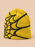 Bonnet motif toile d'araignée jaune et noir, vue trois quarts sur fond pêche sable
