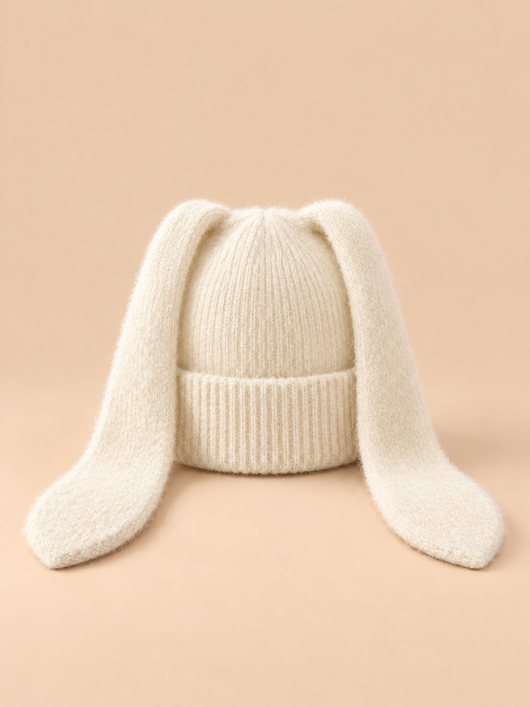 Bonnet à oreilles de lapin, blanc, vue de face sur fond pêche sable.