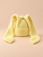 Bonnet à oreilles de lapin, jaune, vue de face sur fond pêche sable.