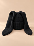 Bonnet à oreilles de lapin, noir, vue de face sur fond pêche sable.