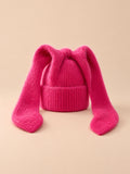 Bonnet à oreilles de lapin, rouge, vue de face sur fond pêche sable.