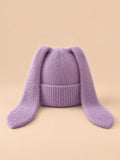 Bonnet à oreilles de lapin, violet, vue de face sur fond pêche sable.