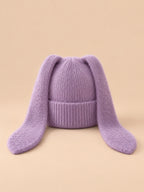 Bonnet à oreilles de lapin, violet, vue de face sur fond pêche sable.