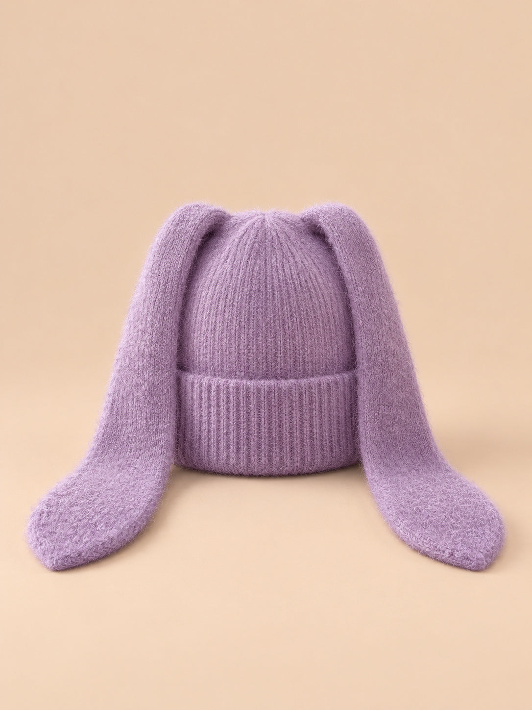 Bonnet à oreilles de lapin, violet, vue de face sur fond pêche sable.