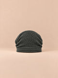 Bonnet oversize en maille gris foncé, vue de face sur fond pêche sable.
