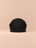 Bonnet oversize en maille noir, vue de face sur fond pêche sable.