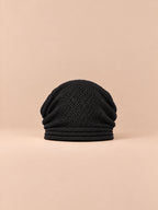 Bonnet oversize en maille noir, vue de face sur fond pêche sable.