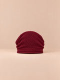 Bonnet oversize en maille rouge, vue de face sur fond pêche sable.