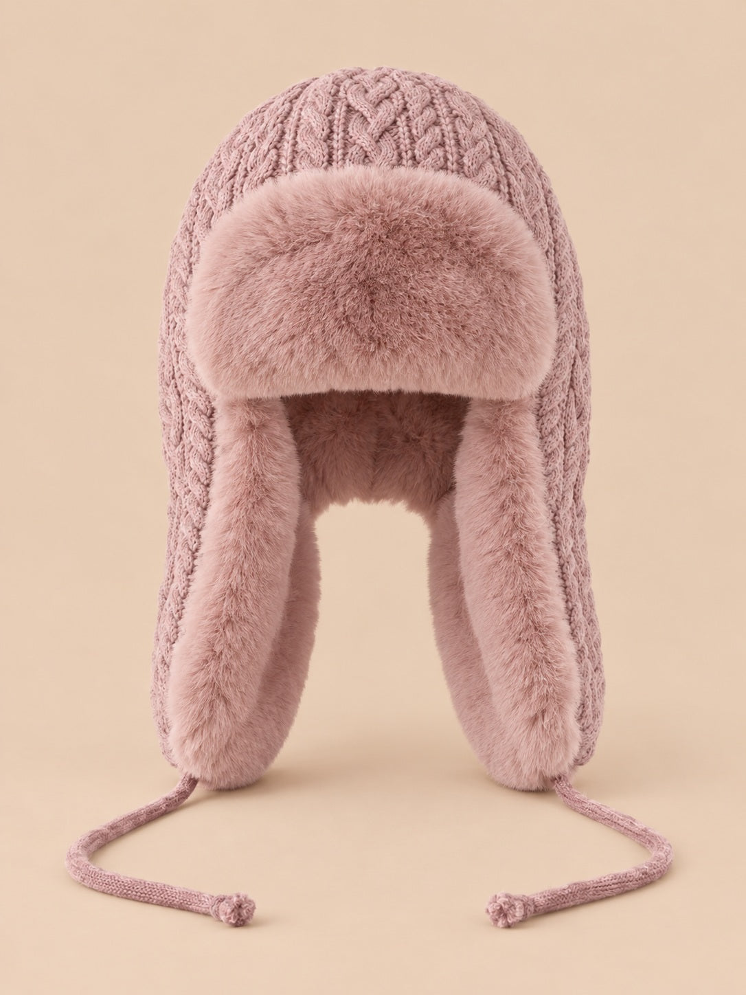 Bonnet péruvien à cache-oreilles rose poudré, vue de face sur fond pêche sable