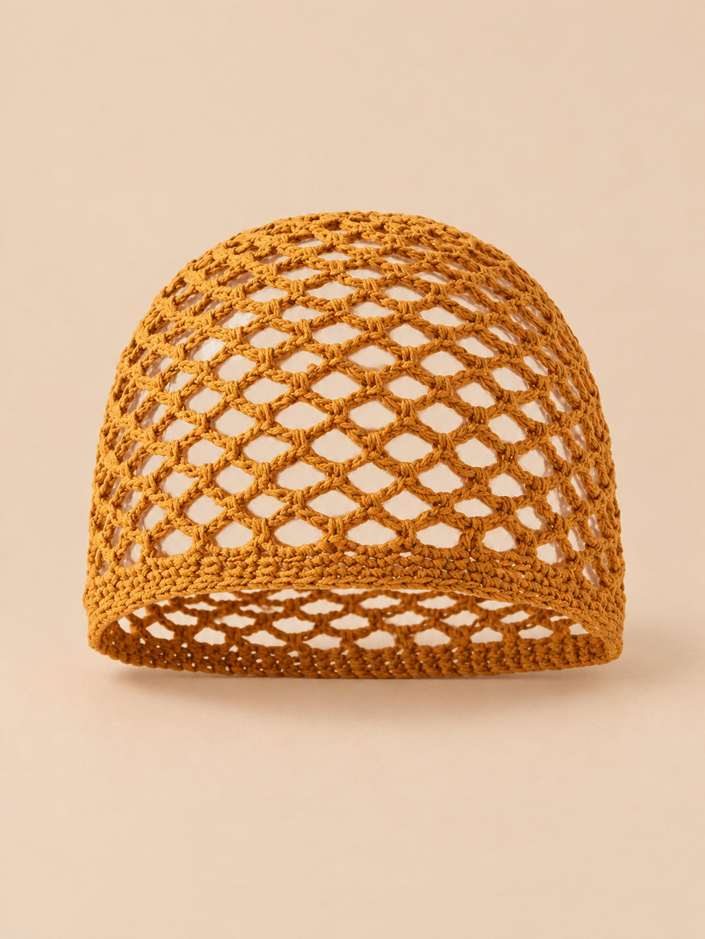 Bonnet fin femme caramel en coton résille ajouré, vue de face sur fond pêche sable