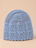 Bonnet turban femme bleu ajouré à fleurs au crochet, vue de face sur fond pêche sable
