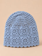 Bonnet turban femme bleu ajouré à fleurs au crochet, vue de face sur fond pêche sable