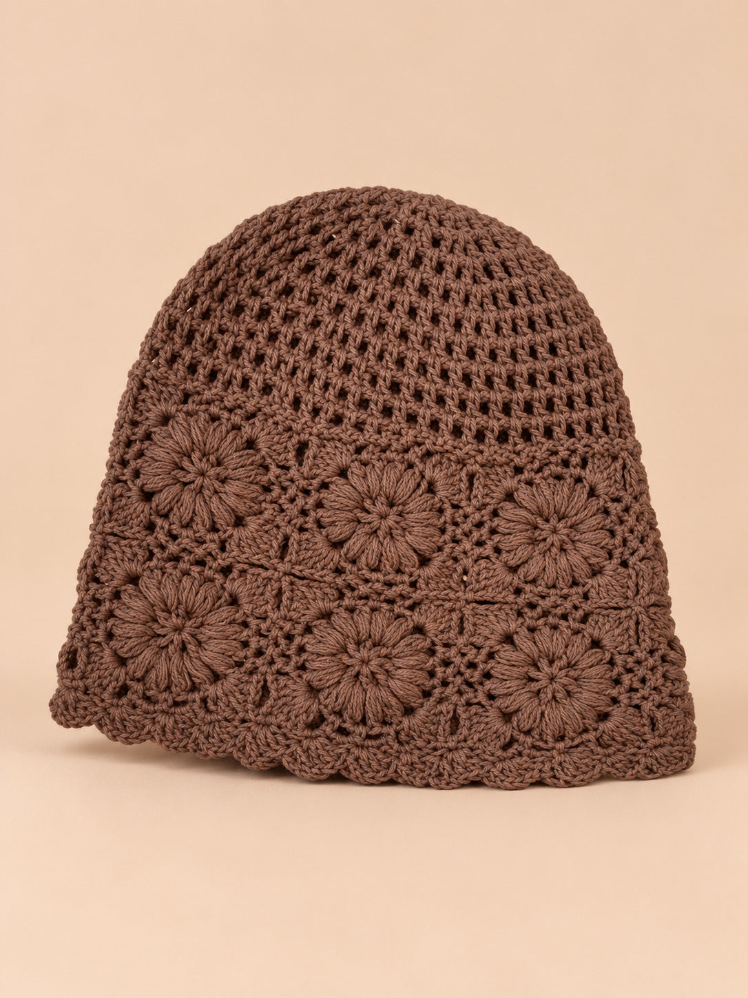 Bonnet turban femme café ajouré à fleurs au crochet, vue de face sur fond pêche sable