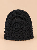 Bonnet turban femme noir ajouré à fleurs au crochet, vue de face sur fond pêche sable