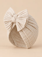 Bonnet turban bébé fille en coton tricoté beige clair, nœud, vue de trois quarts